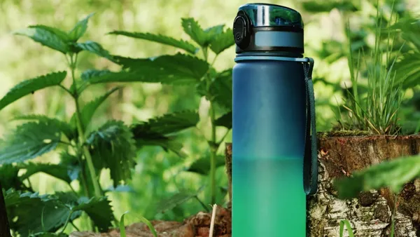Gradient blue bottle standing on a mossy log outdoors